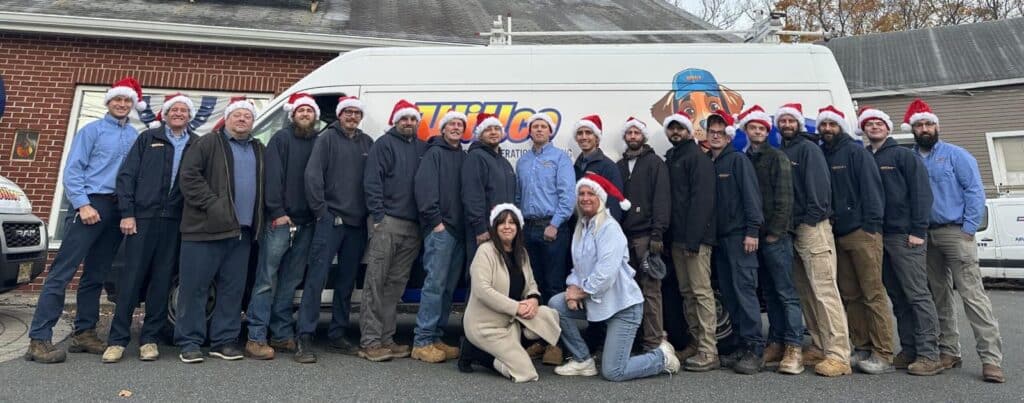 Willco technicians and office staff in holiday hats lined up beside a Willco service van outside the company shop